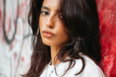 young-woman-in-white-sweatshirt-against-a-red-graffiti-wall-.jpg Young woman in white sweatshirt against a red graffiti wall.